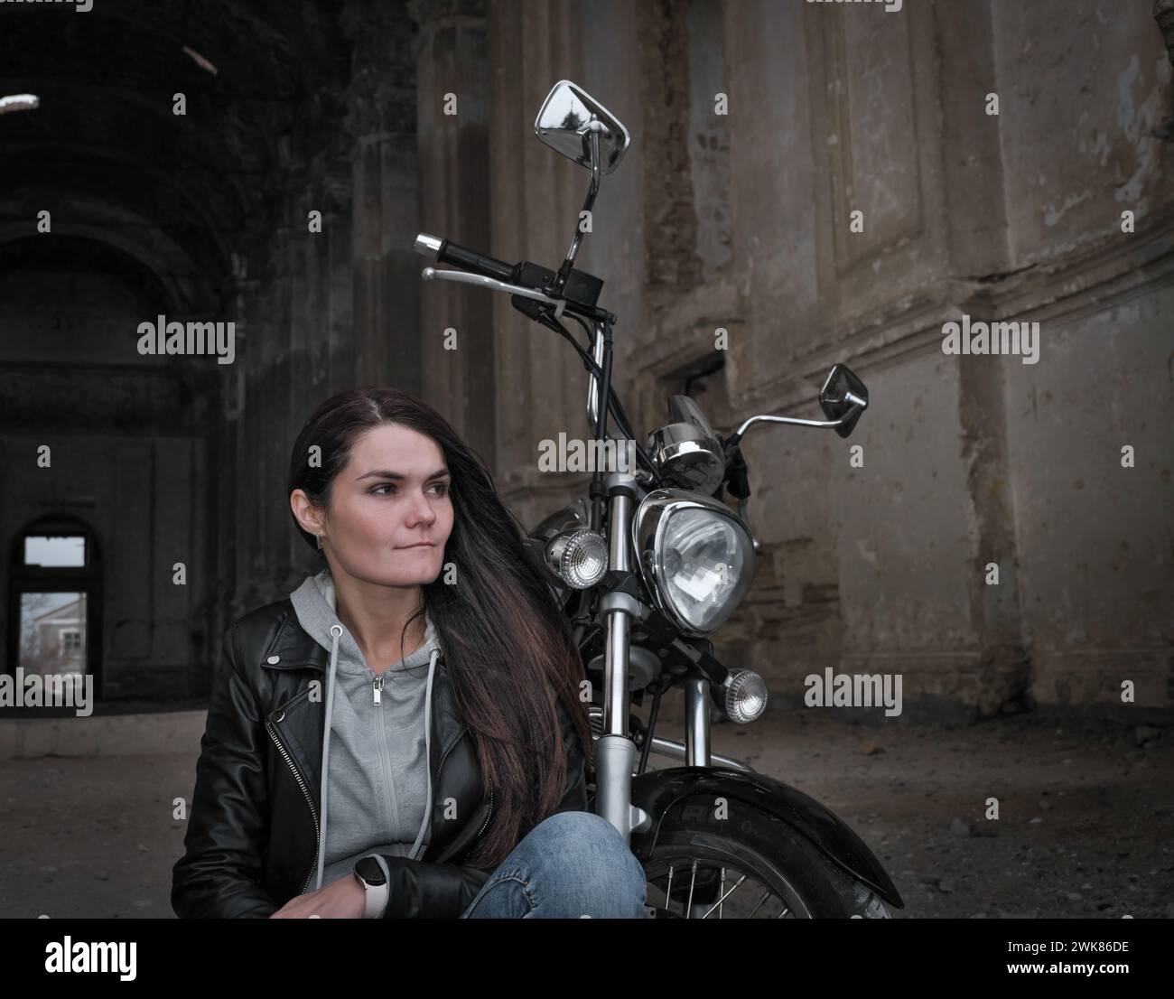 Ritratto di una donna in una giacca di pelle vicino a una moto d'epoca Foto Stock