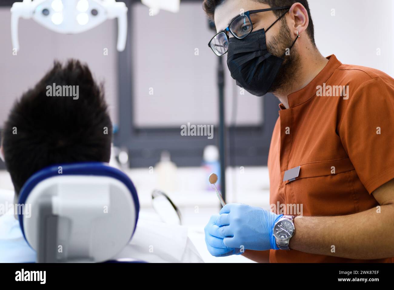 Un dentista in profonda concentrazione mentre esamina il suo paziente, fornendo cure esperte con una precisione che assicura un sorriso sano Foto Stock