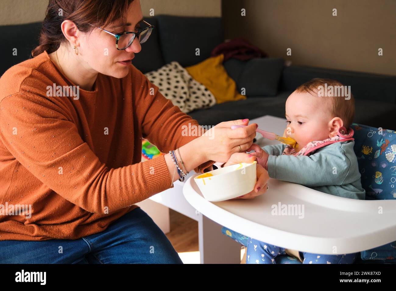 Mamma che dà da mangiare alla sua bambina con purè di verdure e pollo. Foto Stock