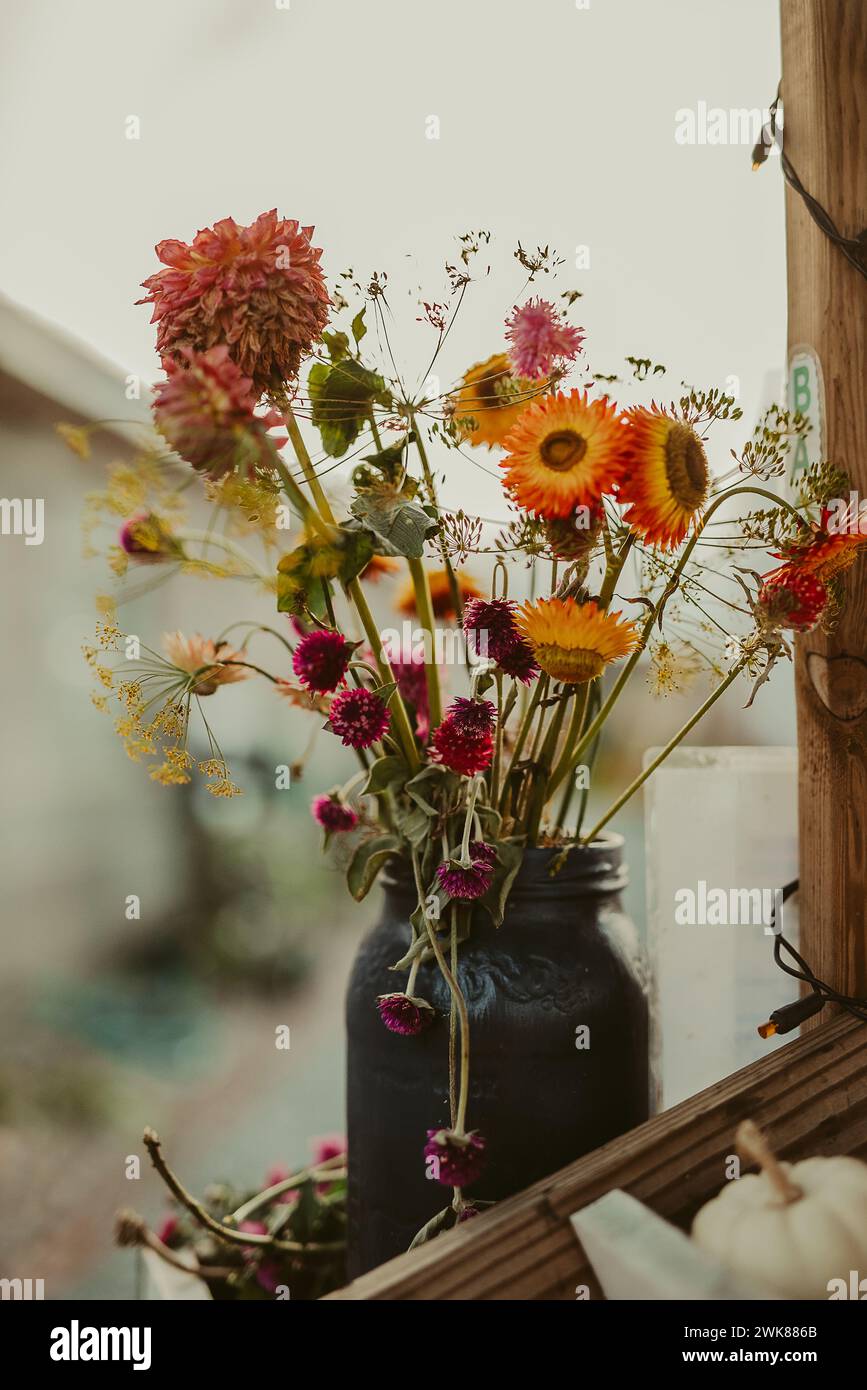 I fiori cadono in un vaso massone rustico su un banco di fattoria Foto Stock