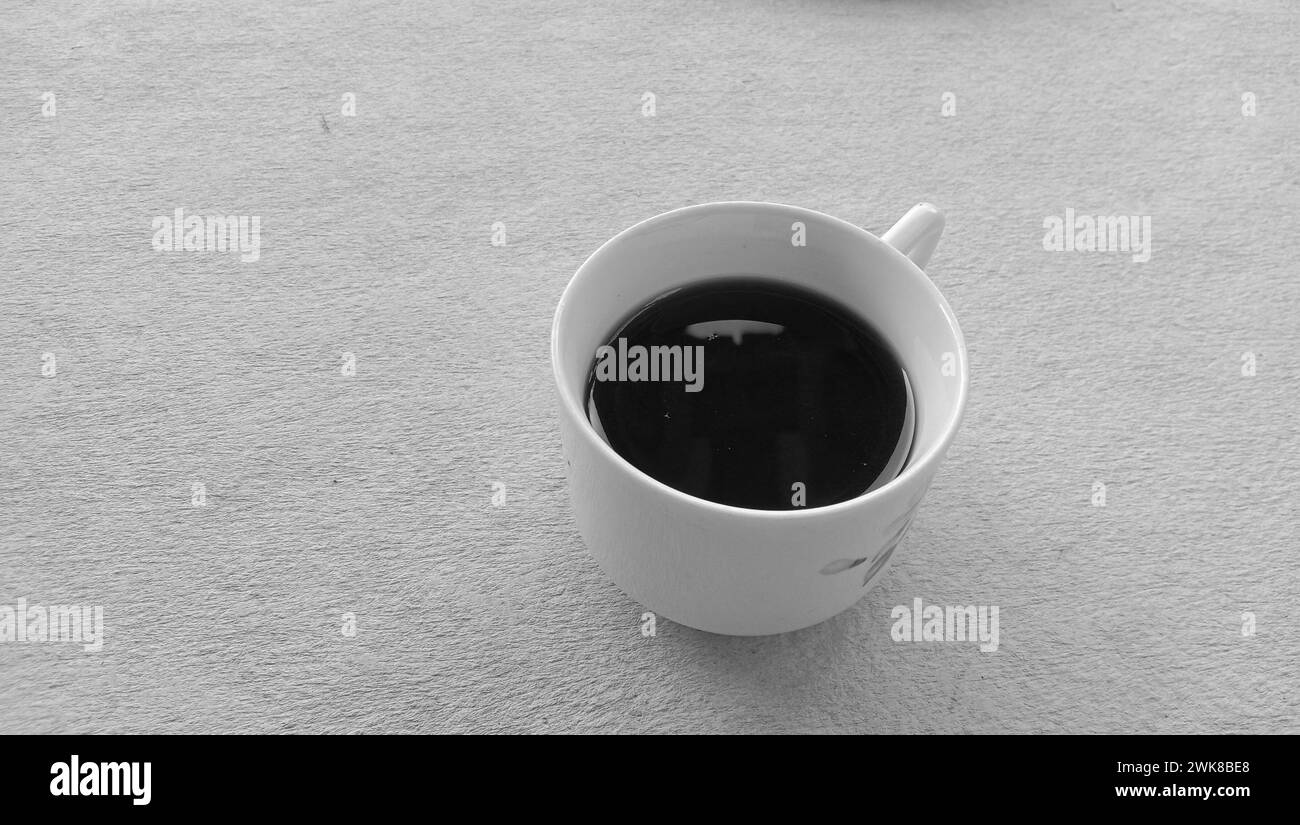 Foto di una tazza di caffè nera in una tazza bianca su sfondo bianco Foto Stock