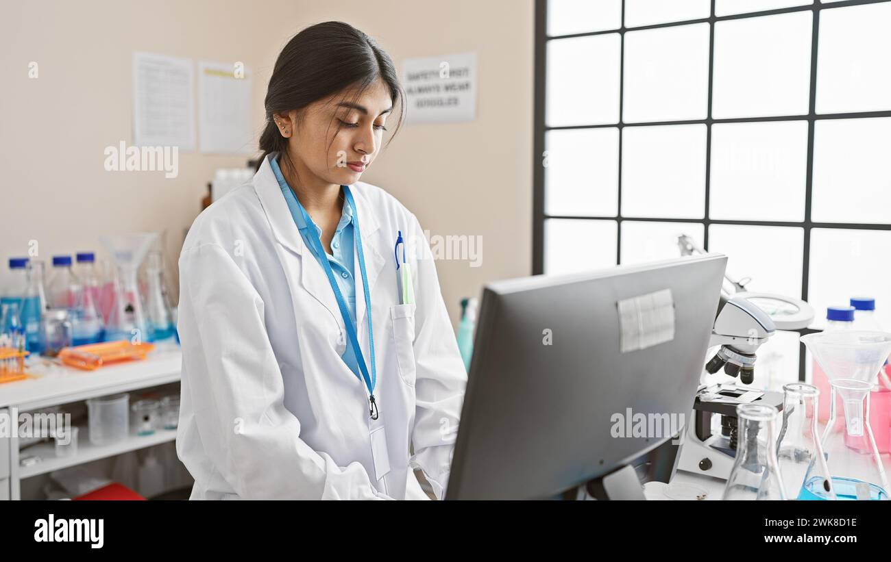 Scienziata donna dell'asia meridionale che si concentra sullo schermo del computer in laboratorio. Foto Stock