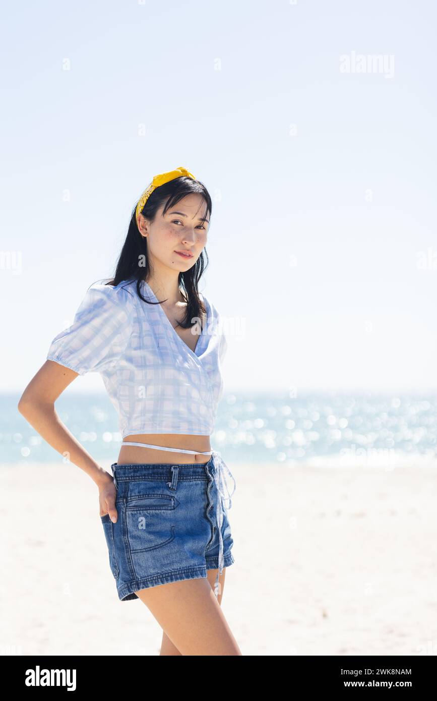 Giovane donna birazziale posa su una spiaggia soleggiata, con spazio per copiare Foto Stock