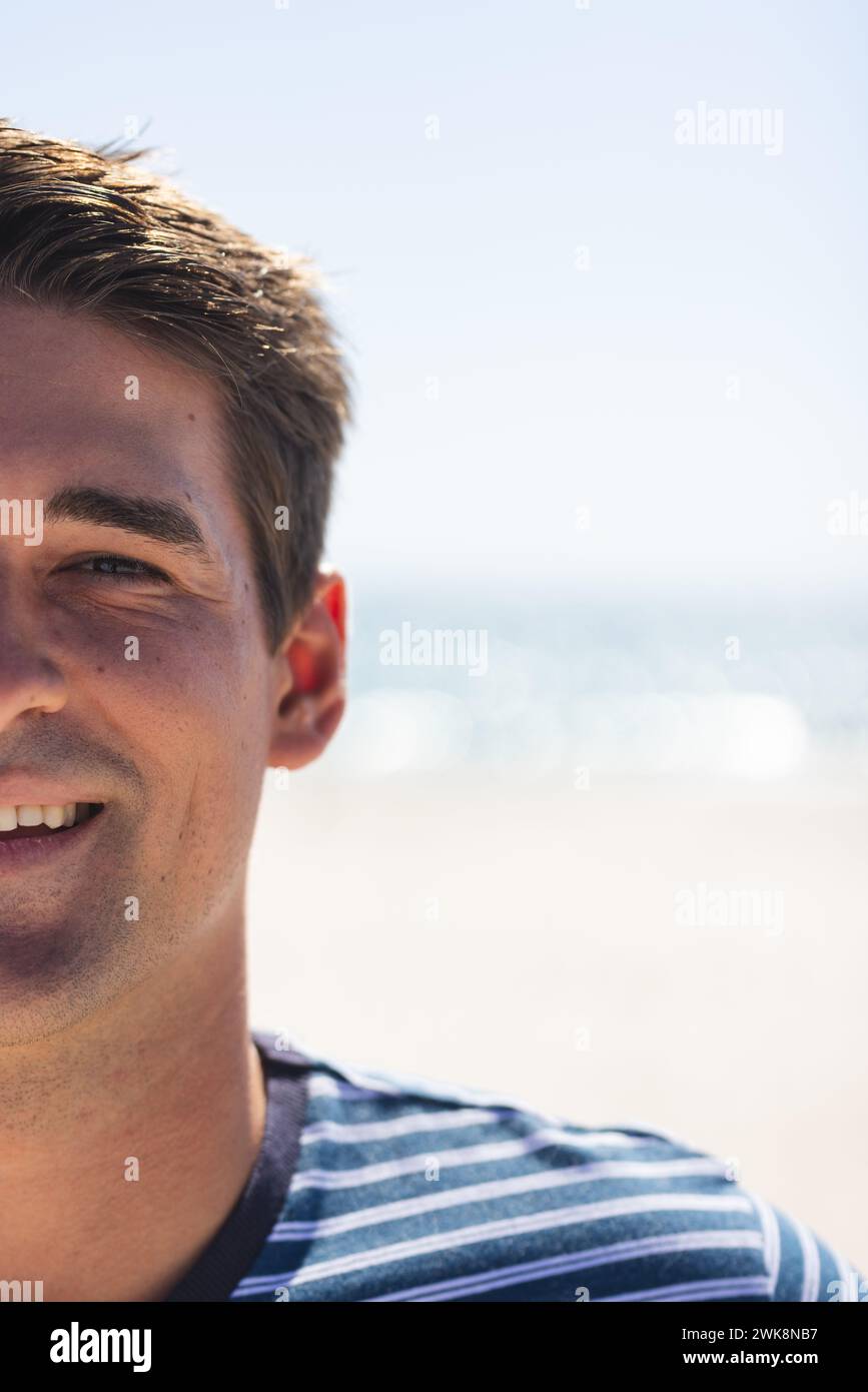 Un giovane uomo caucasico sorride alla spiaggia, con spazio per copiare Foto Stock