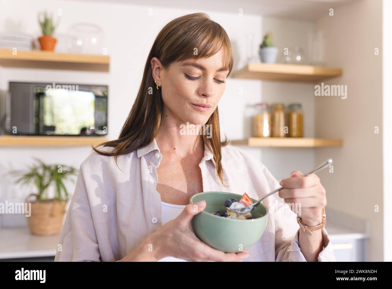 Una giovane donna caucasica gode di un pasto sano da una ciotola Foto Stock