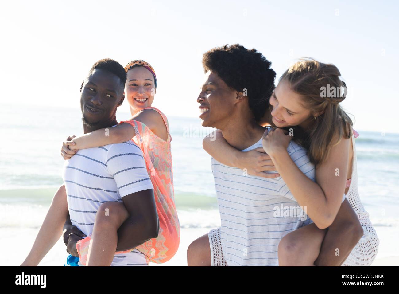 Diversi amici si divertono con un giro in piggyback sulla spiaggia Foto Stock