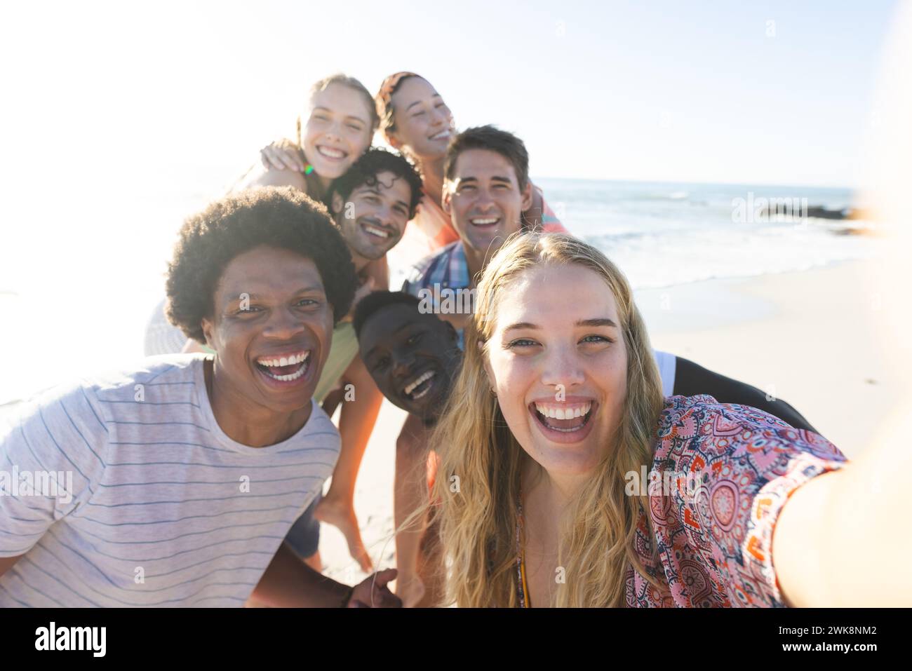 Amici diversi sorridono per un selfie su una spiaggia soleggiata Foto Stock