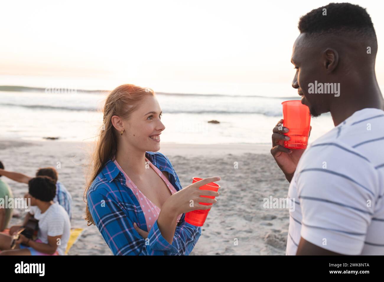 La giovane donna caucasica e l'uomo afroamericano si godono una festa in spiaggia Foto Stock