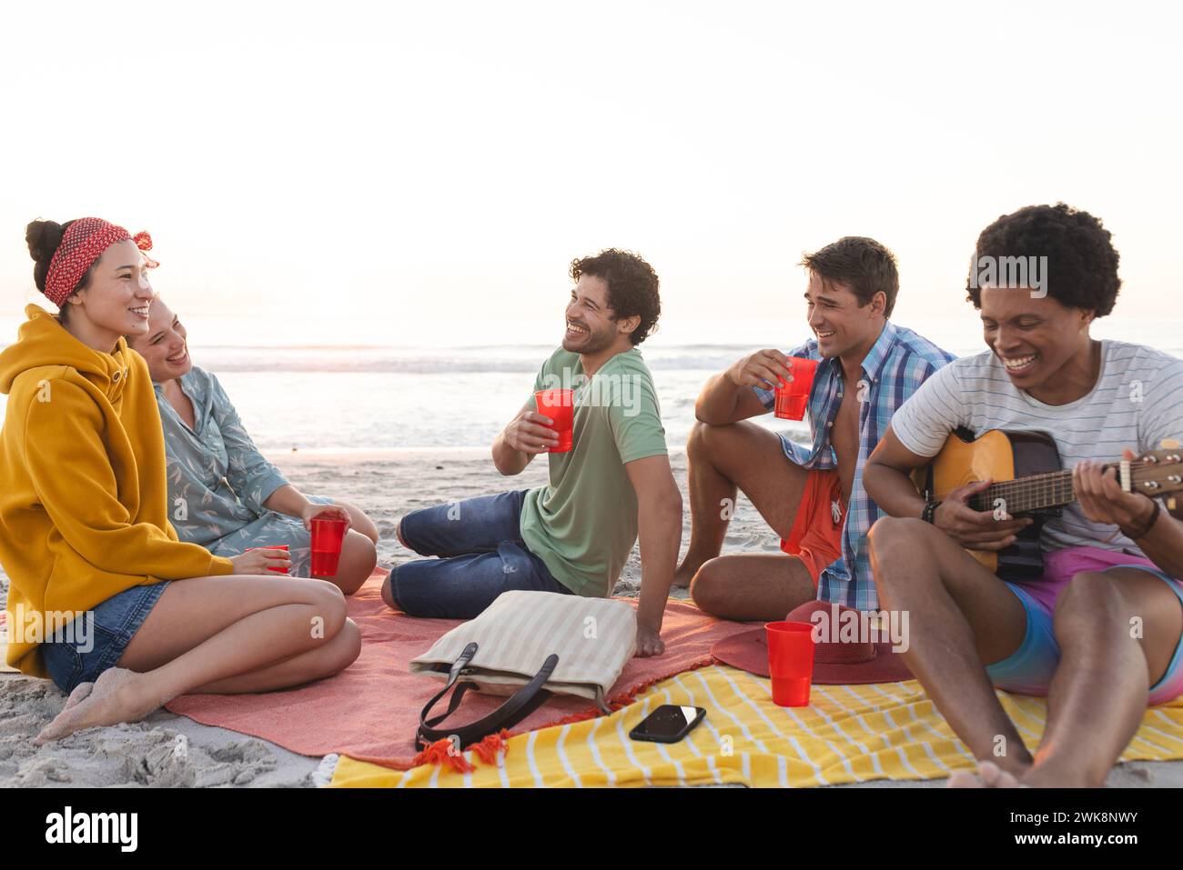 Amici diversi si godono una riunione sulla spiaggia e una festa Foto Stock