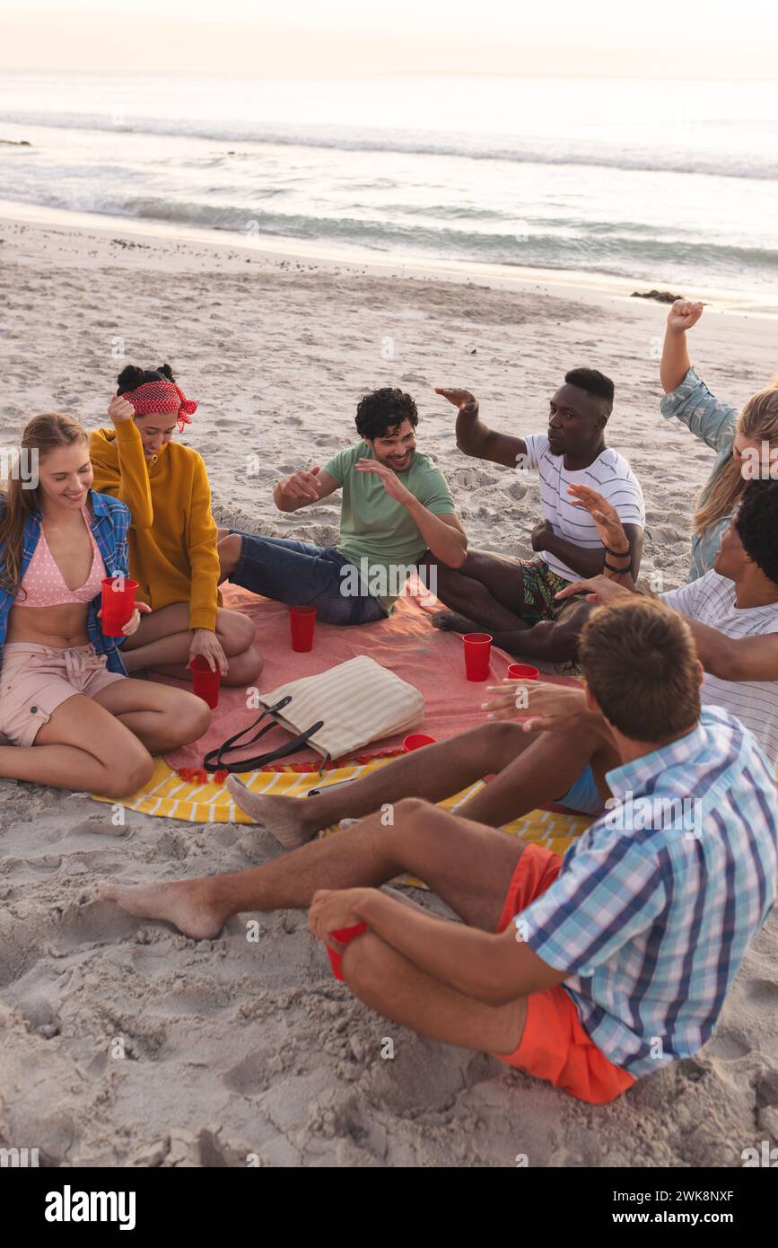 Diversi gruppi di amici si godono una festa in spiaggia al tramonto, con spazio per copiare Foto Stock
