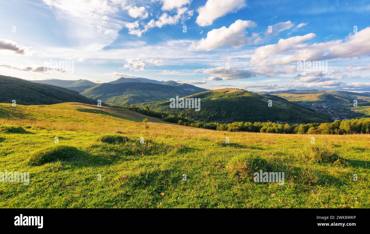 paesaggio rurale con prati erbosi. catena montuosa lontana sotto un cielo con nuvole. splendido scenario della campagna dei carpazi in una giornata di sole in e Foto Stock