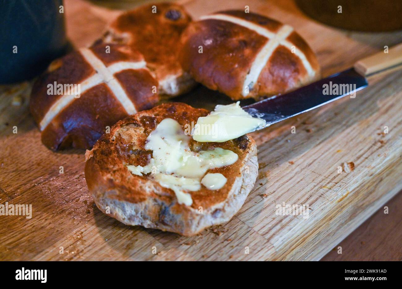 Panini Hot Cross tostati con burro, un piatto tradizionale da colazione consumato a Pasqua Foto Stock