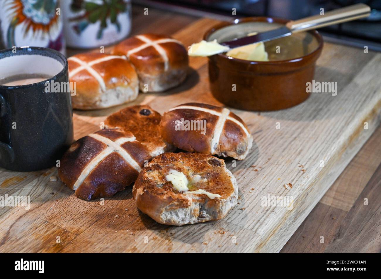 Panini Hot Cross tostati con burro, un piatto tradizionale da colazione consumato a Pasqua Foto Stock