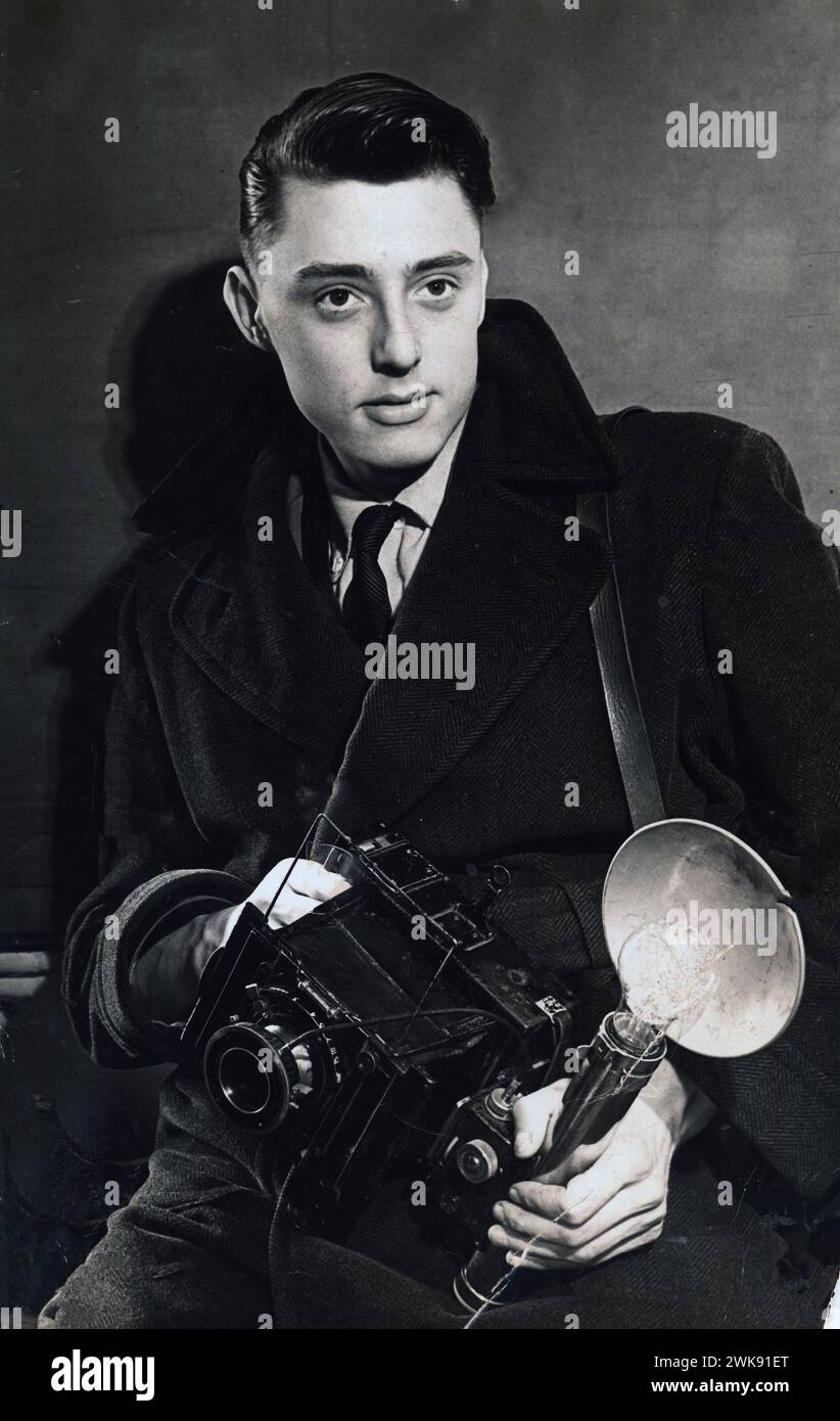 Un giovane fotografo tiene in mano una fotocamera VN Press con attacco per lampadina flash. La macchina fotografica a piastre è stata ampiamente utilizzata dalla stampa provinciale fino ai primi anni '60 Foto Stock