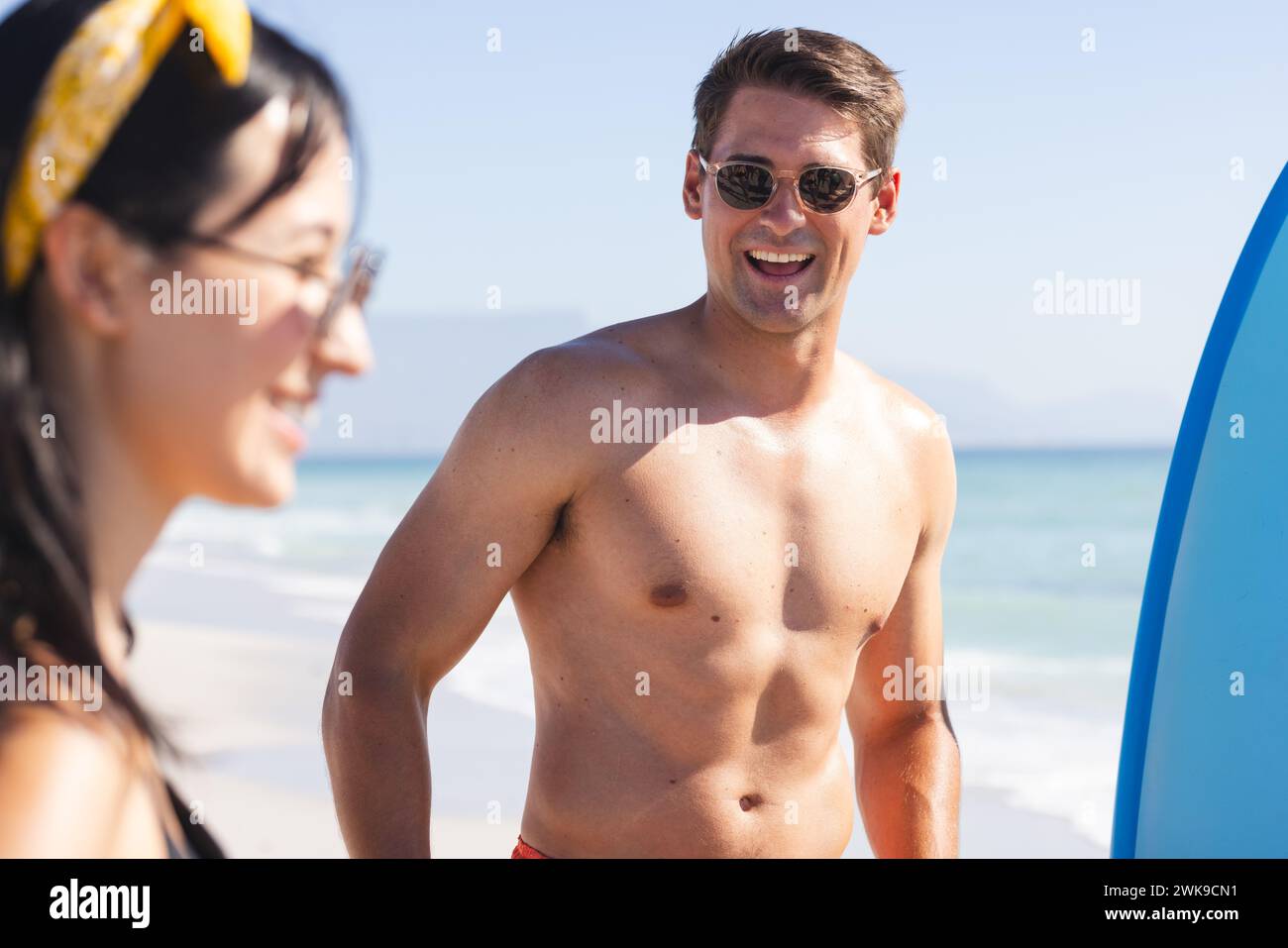 Giovane uomo caucasico e donna birazziale si godono una giornata di sole sulla spiaggia Foto Stock
