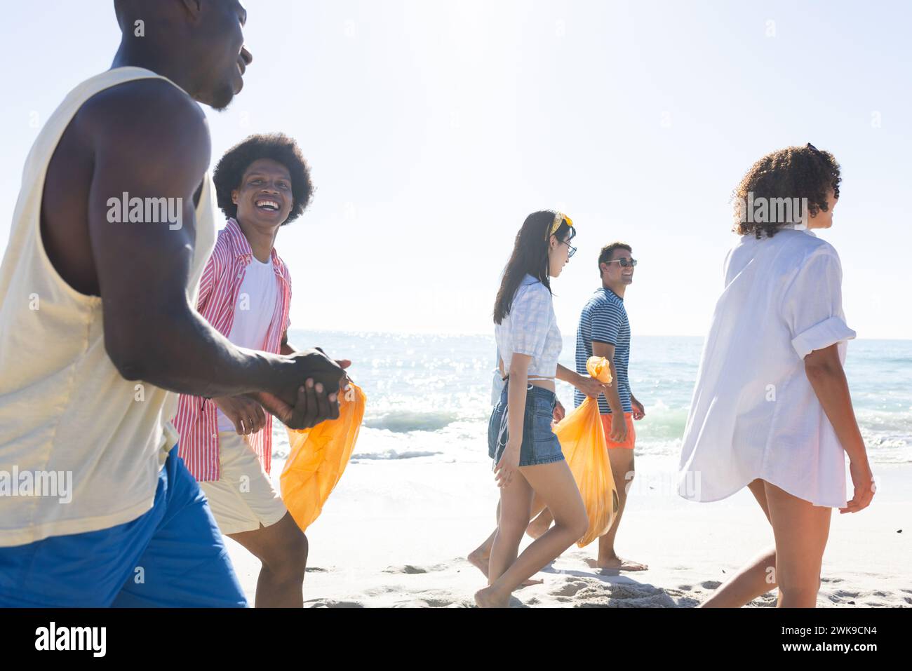 Gruppi diversi di amici trascorrono una giornata in spiaggia raccogliendo rifiuti Foto Stock