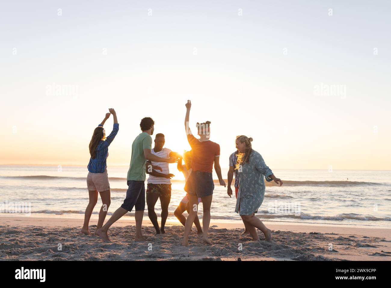 Gruppi diversi di amici si godono un tramonto sulla spiaggia Foto Stock