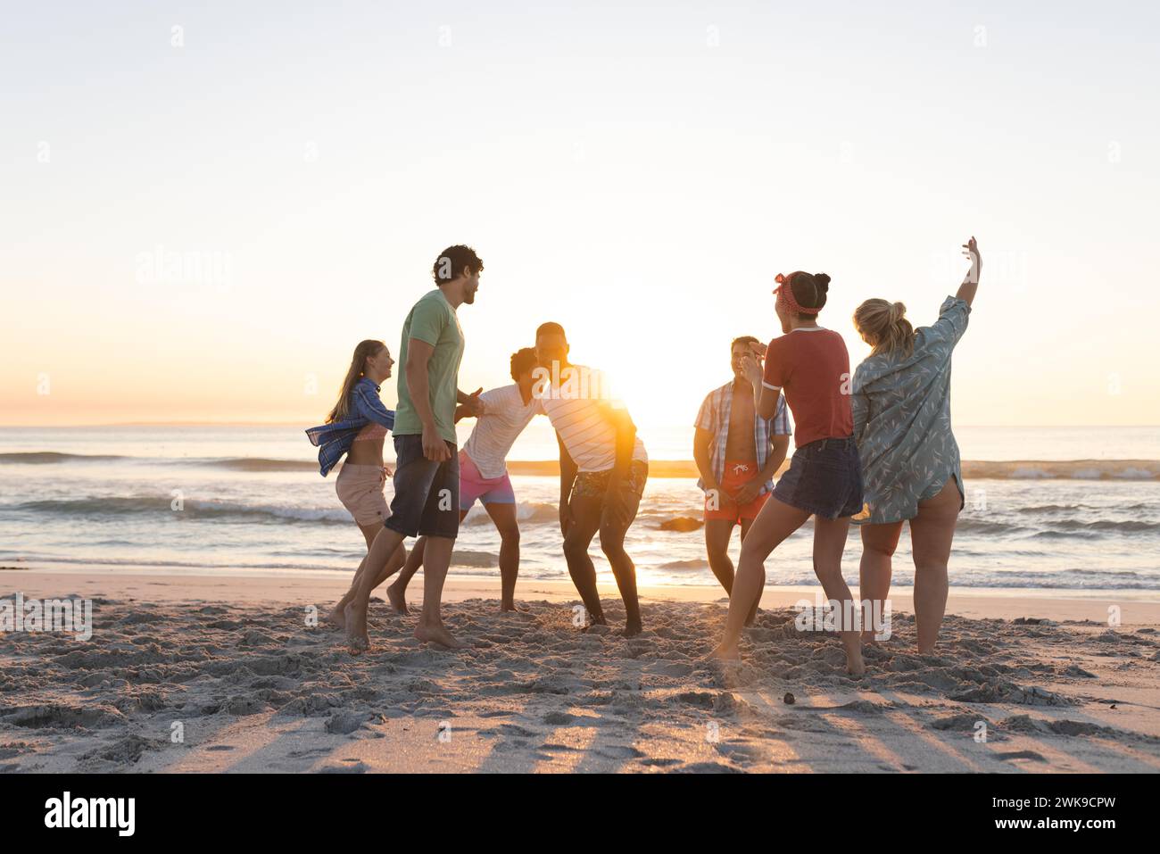 Gruppi diversi di amici si godono una gita in spiaggia al tramonto Foto Stock