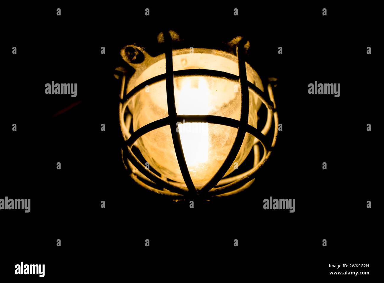 Luce al buio. Vecchia lampada con luce calda su sfondo scuro. Foto Stock