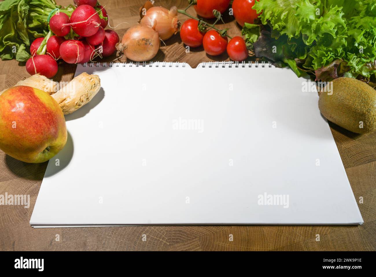 Notebook a spirale con carta bianca bianca bianca e alimenti freschi come verdura e frutta su un tavolo in legno rustico, spazio per un piano nutrizionale, una dieta o una guarigione Foto Stock