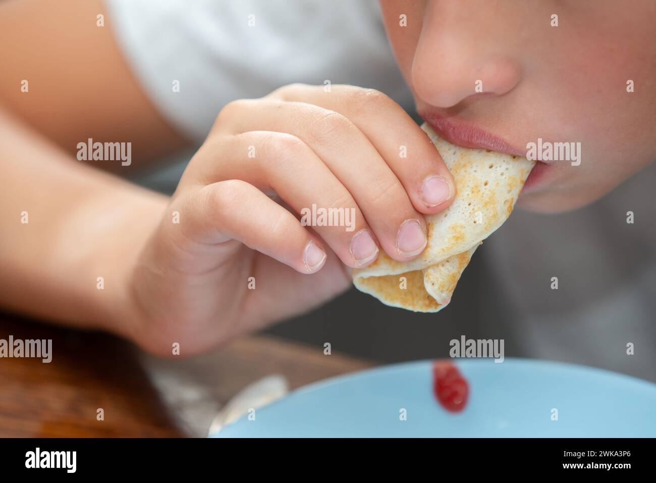 Il bambino mangia un pancake. Ci sono prodotti da forno. Foto Stock