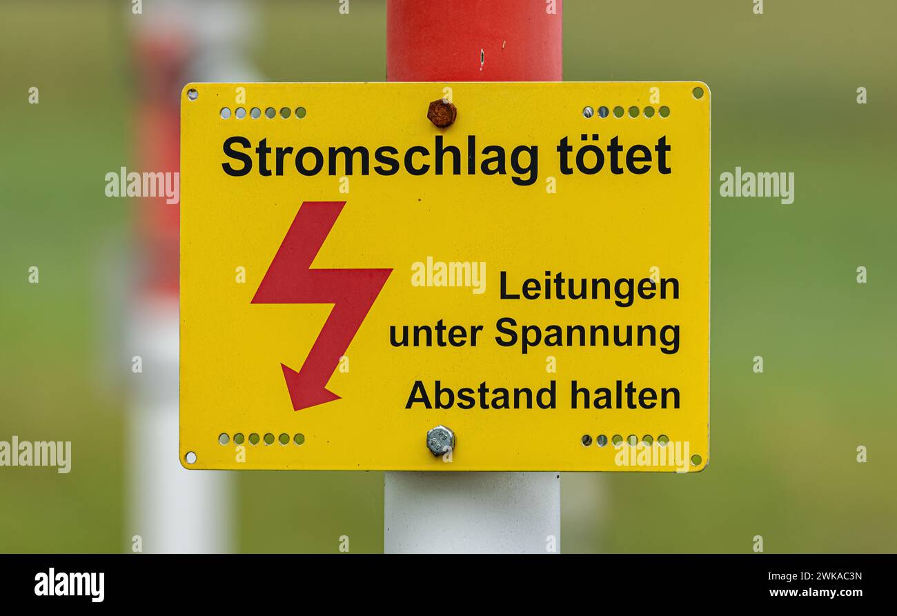 Ein Schild bei einem Bahnübergang warnt vor einem tödlichen Stromschlag der Oberleitungen. (Bäretswil, Schweiz, 02.07.2023) Foto Stock