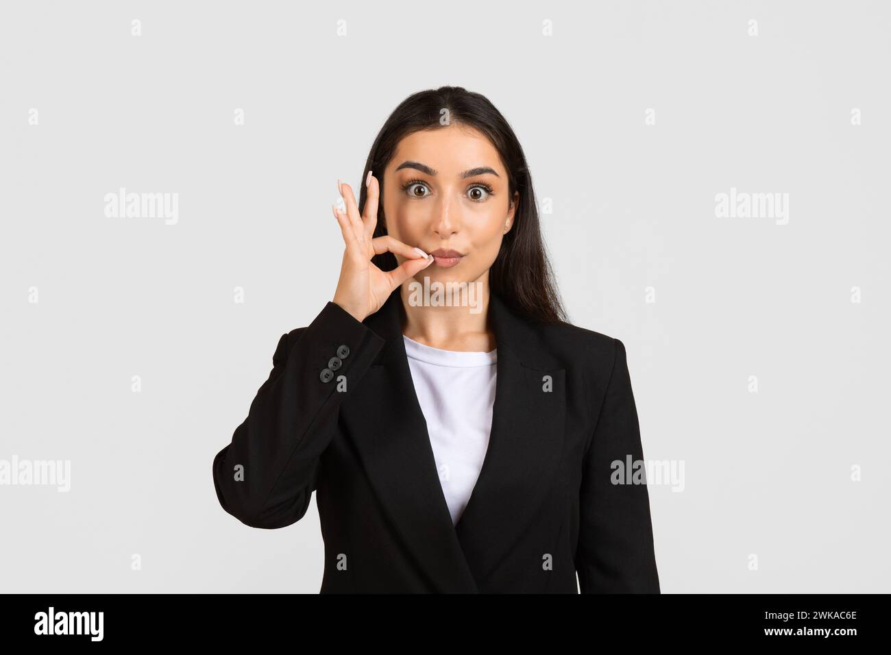 Giovane donna d'affari giocosa che fa un gesto silenzioso Foto Stock