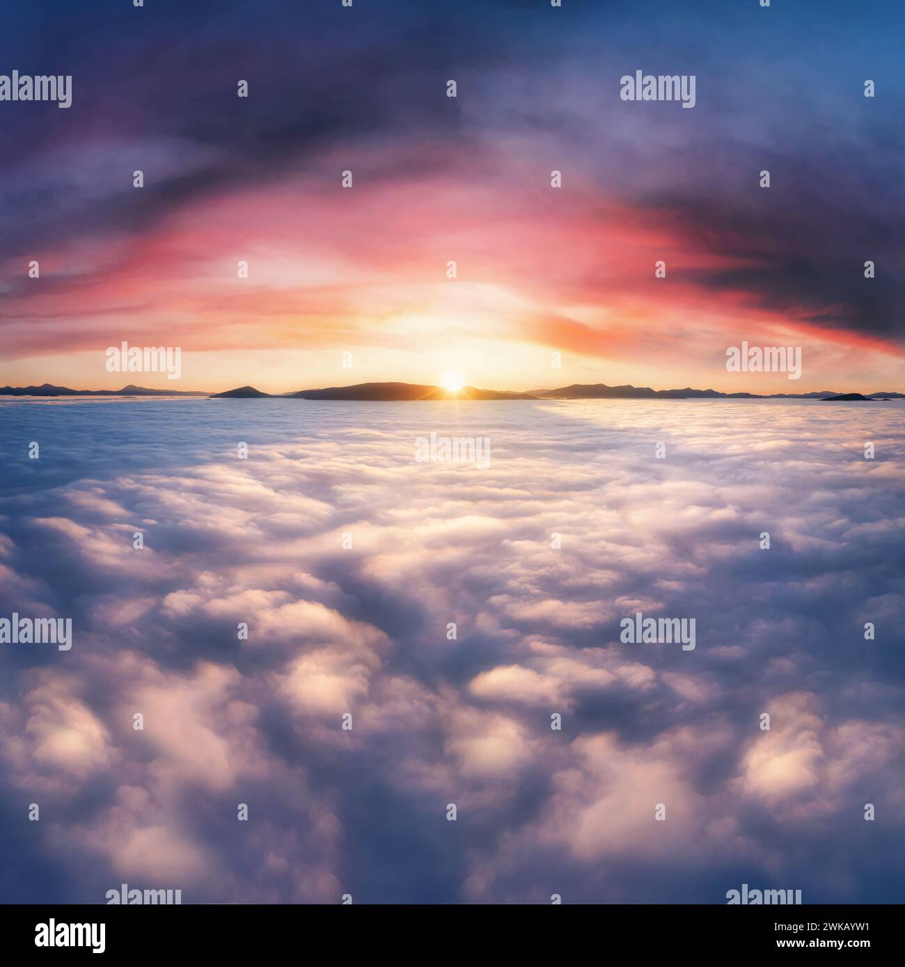Nuvole spesse nelle montagne all'alba. Splendido paesaggio aereo con una fitta nebbia contro il suggestivo cielo del tramonto. Foto Stock
