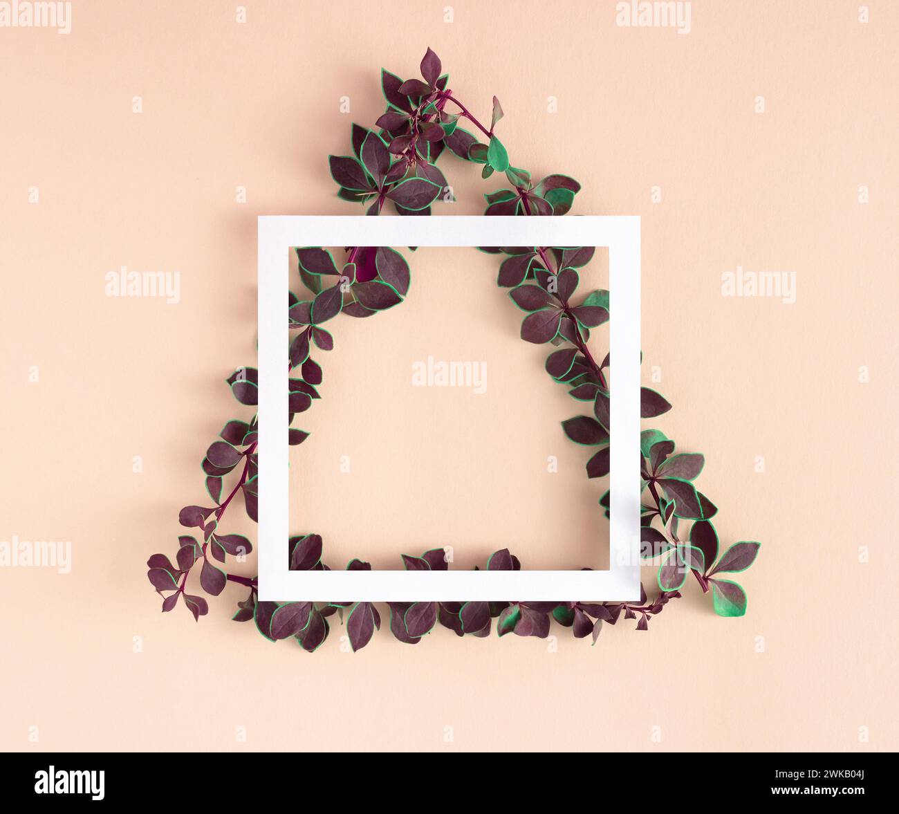 Layout geometrico creativo composto da rami con foglie verdi a forma di triangolo e cornice in carta su sfondo color beige pastello. Foto Stock