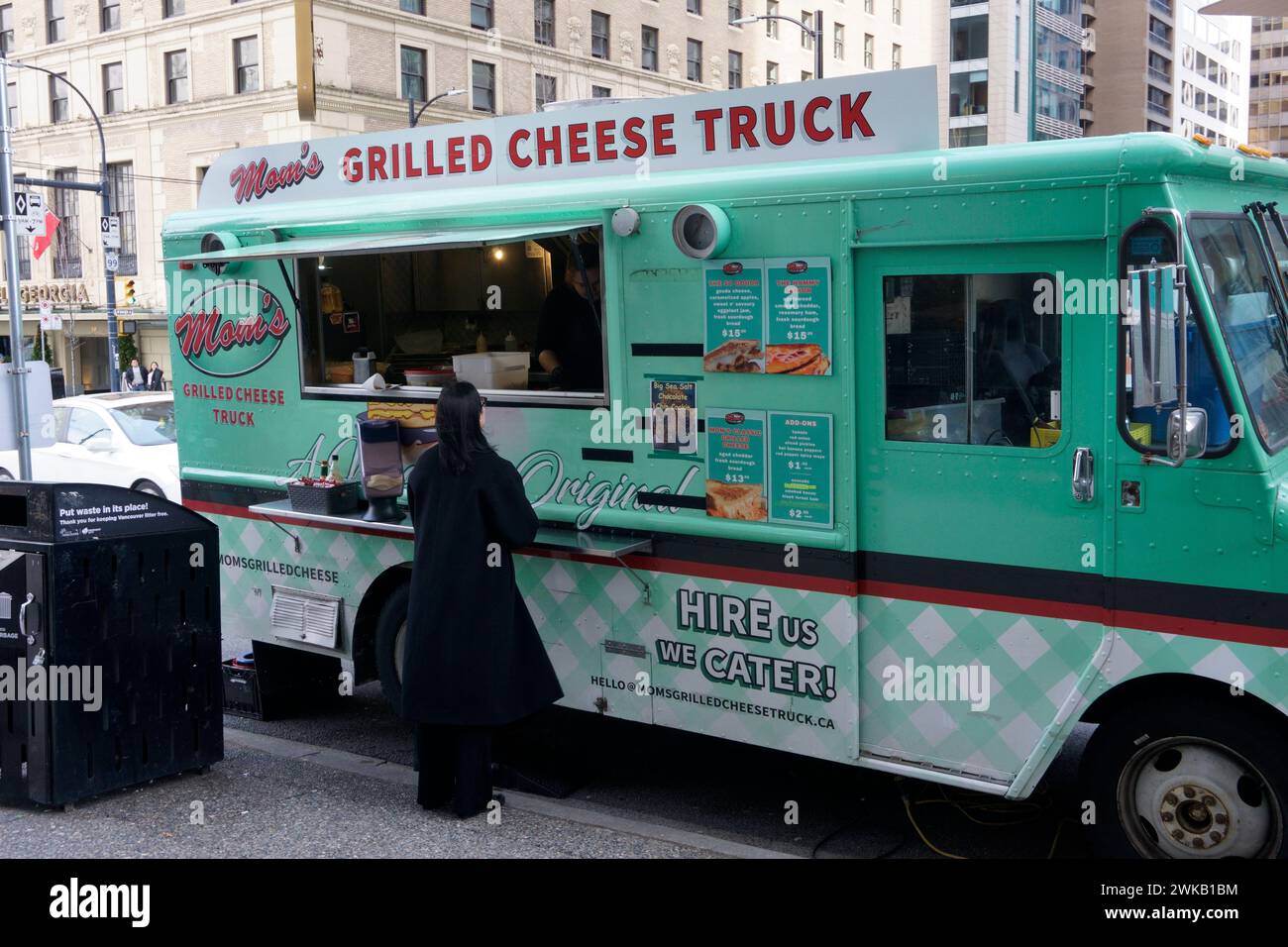 Donna che ordina il cibo da Mom's Grilled Cheese Truck nel centro di Vancouver, British Columbia, Canada Foto Stock