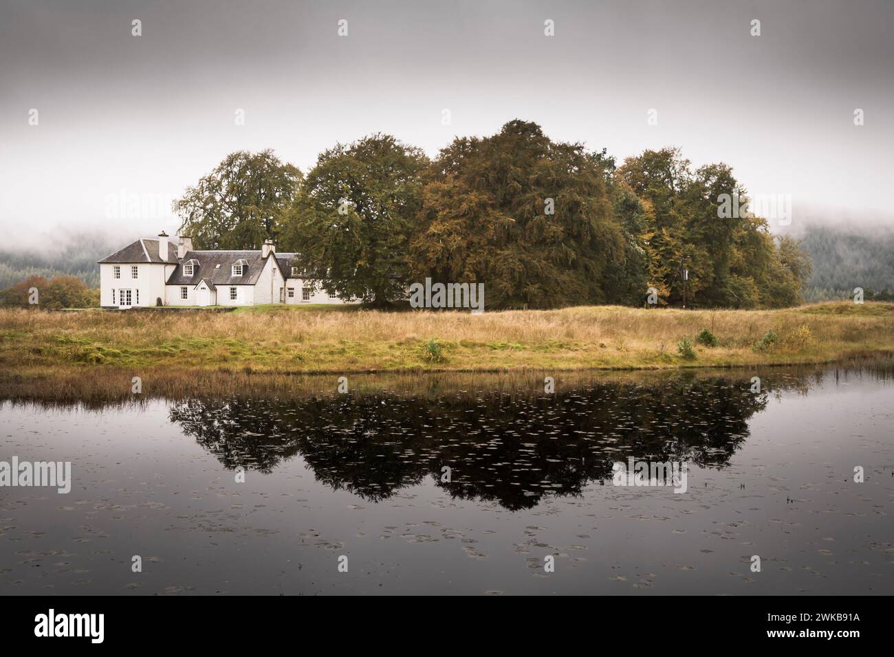 Grande casa bianca in Scozia. Casa di campagna remota accanto al lago nel paesaggio scozzese. Highland, Scozia, Regno Unito Foto Stock