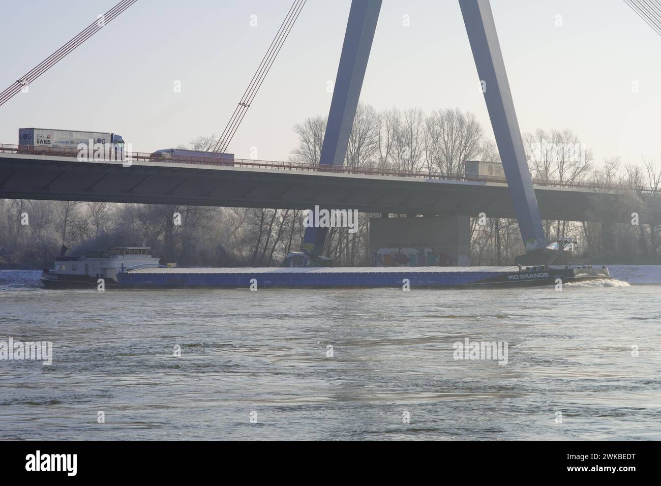 Guidando un camion attraverso un ponte affollato mentre un traghetto scivola con grazia lungo il fiume Reno sottostante. Foto Stock