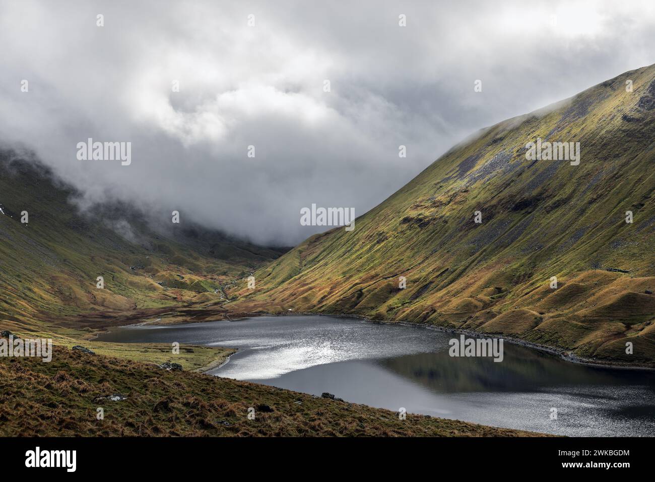 Il sole si infrangono attraverso una fitta nuvola e illuminano Hayeswater, Lake District, Cumbria, Regno Unito Foto Stock