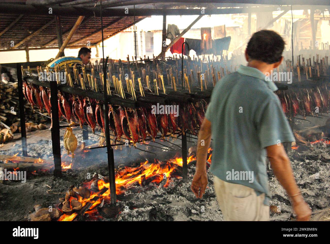Produzione di pesce affumicato che utilizza carni di tonno striato in un'industria domestica a Bitung, Sulawesi settentrionale, Indonesia. I contributi delle conoscenze indigene all'innovazione tecnologica offrono un'ampia gamma di opzioni per la gestione, tra l'altro, della sicurezza alimentare, secondo la relazione 2023 del gruppo intergovernativo di esperti sui cambiamenti climatici (IPCC). Popolarmente conosciuto come cakalang fufu, il tonno affumicato è considerato un alimento indigeno esotico e potrebbe diventare una soluzione alternativa per affrontare gli impatti del cambiamento climatico sull'oceano. Foto Stock