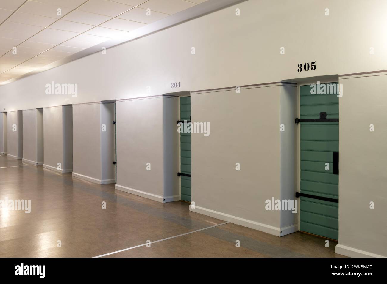 Una fila di porte di celle in un corridoio di prigione Foto Stock