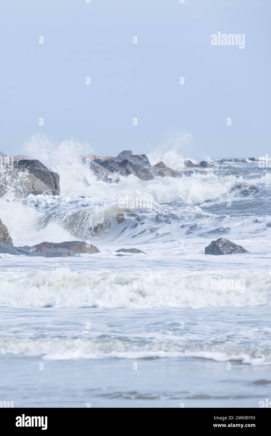 Onde che si infrangono sulle rocce sulla spiaggia Foto Stock