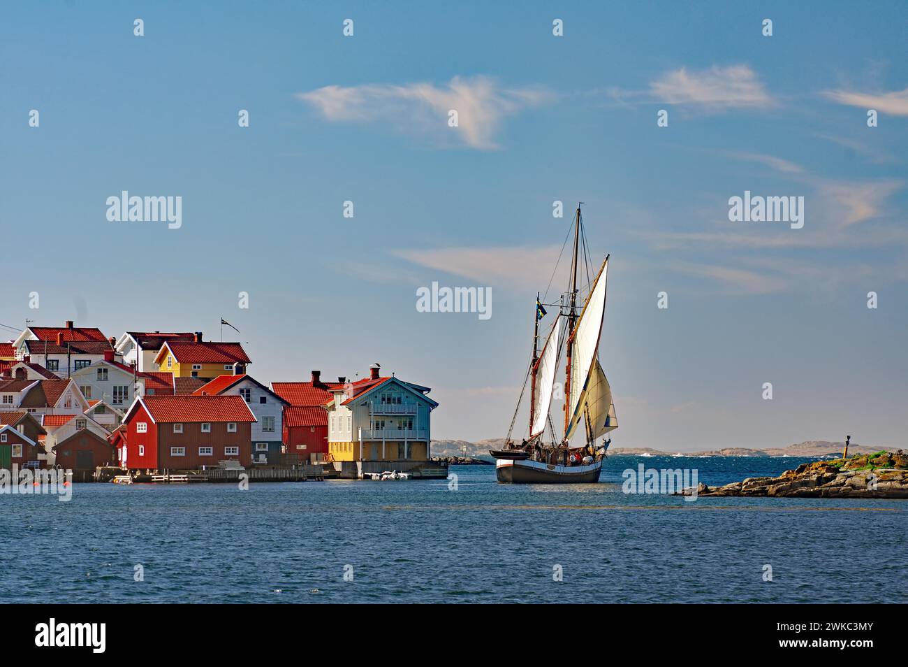 Nave a vela che lascia un piccolo porto sulla costa occidentale svedese, case di legno, Kaeringon, Svezia Foto Stock