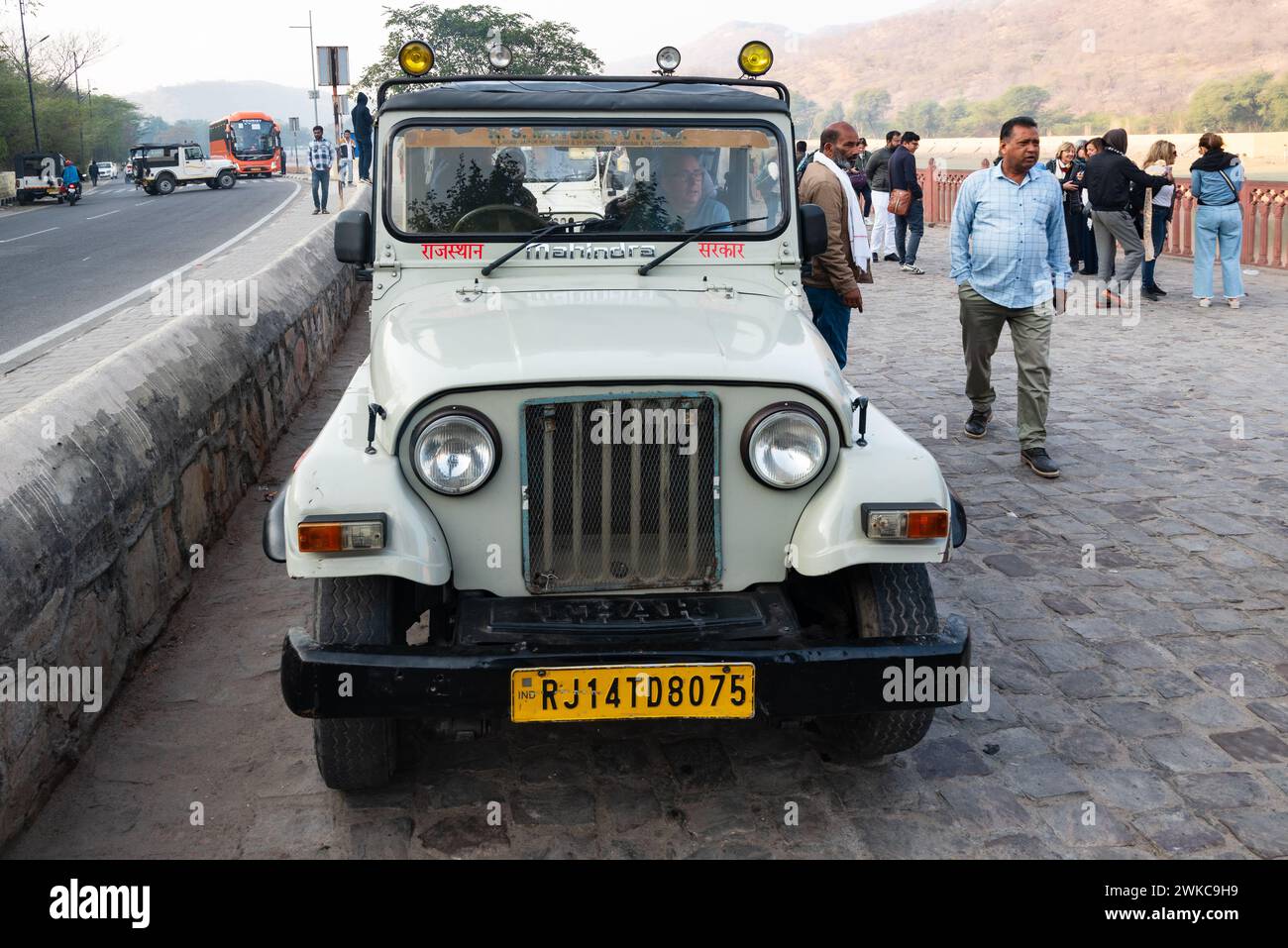 Amer, Jaipur, India. 16 febbraio 2024. Vivace scena di strada con turisti e guide che si riuniscono intorno a una jeep bianca che li trasporterà al famoso Foto Stock