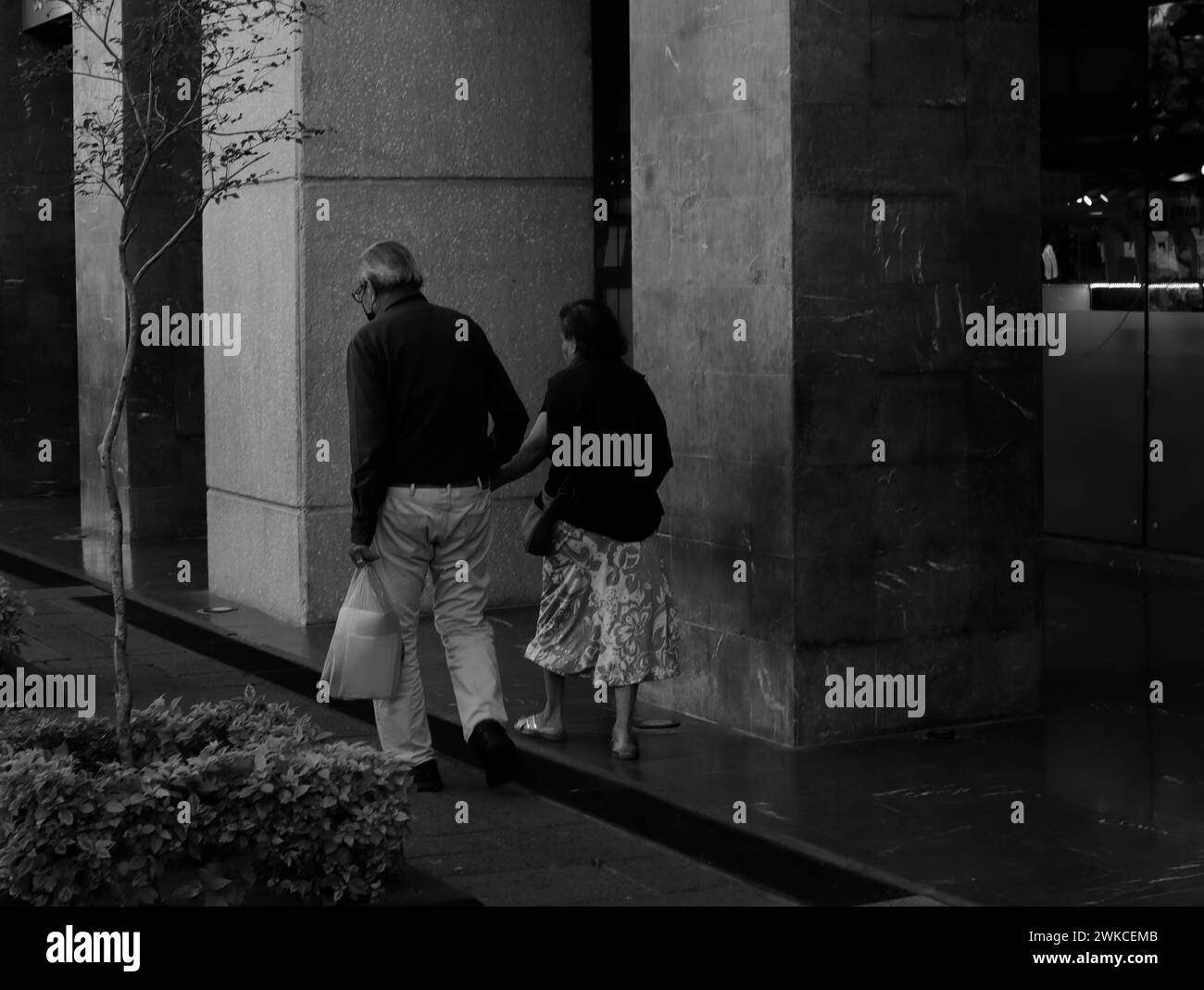 Una vecchia coppia che cammina lungo il marciapiede insieme. Foto Stock