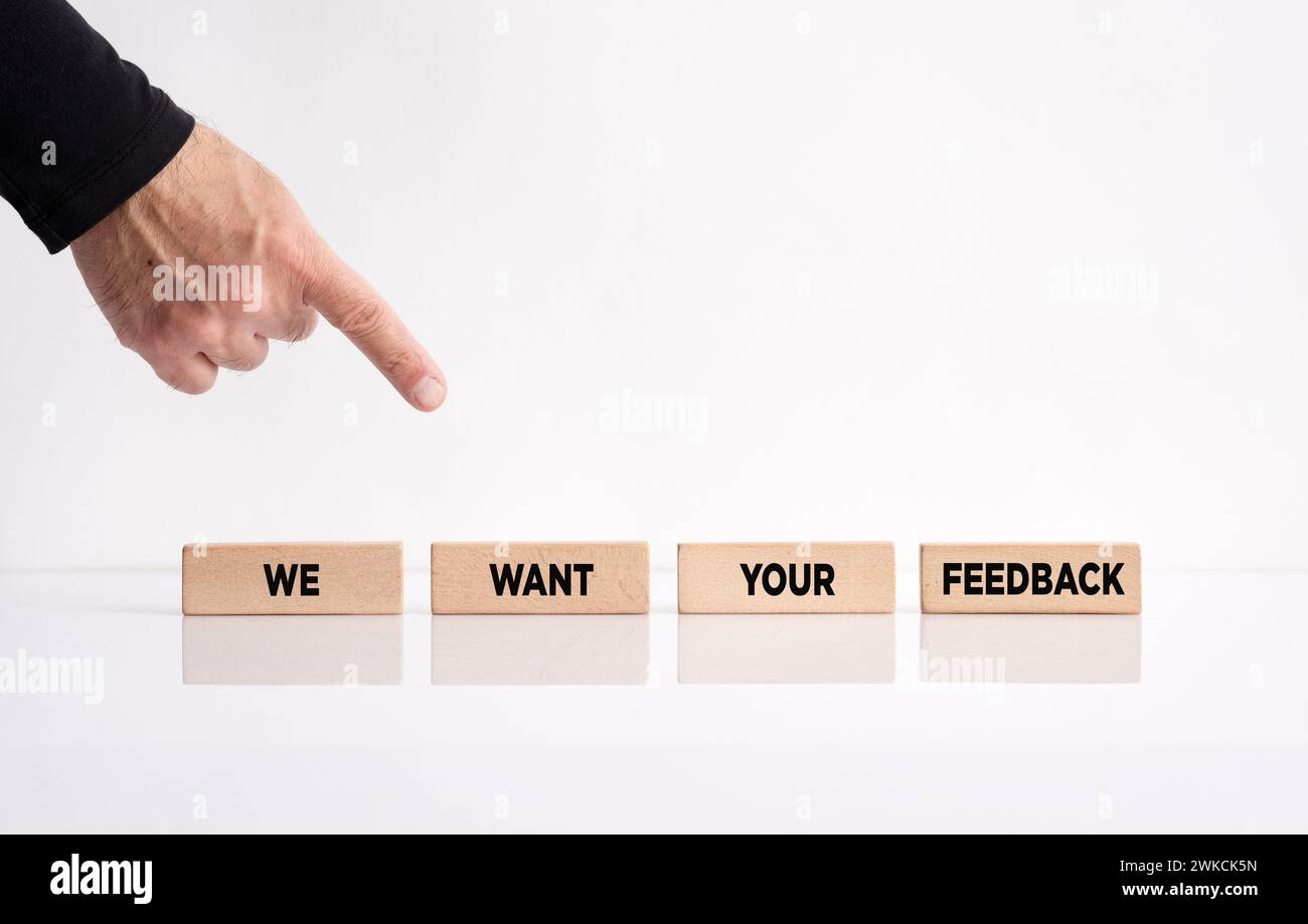 Feedback e valutazione dei clienti o degli utenti. Mano che punta verso i blocchi di legno con il messaggio vogliamo il tuo feedback. Foto Stock