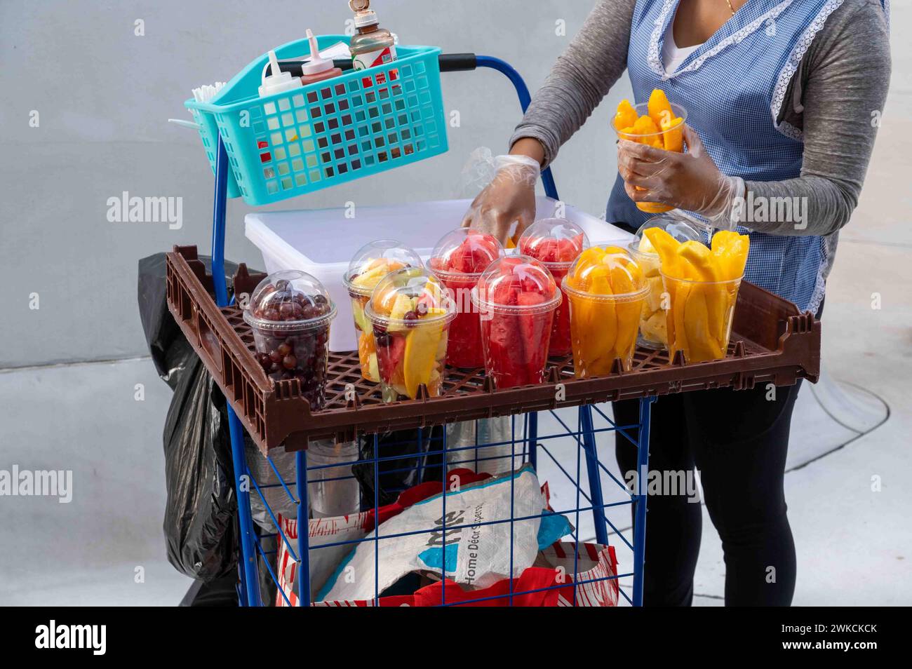 Il venditore di frutta fresca riempie le tazze di plastica con mango tagliato a New York Foto Stock