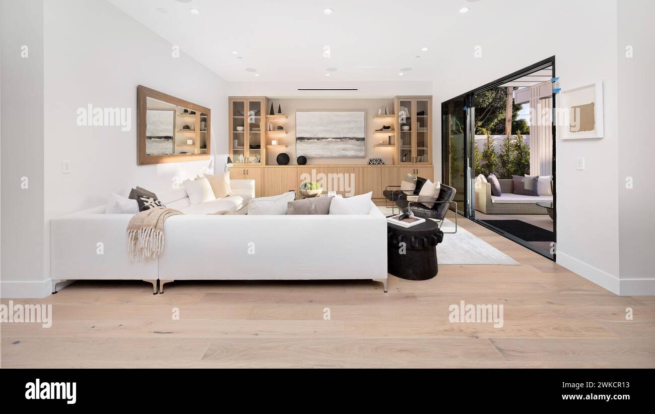 Spazioso soggiorno con pavimenti in legno duro e pareti bianche Foto Stock