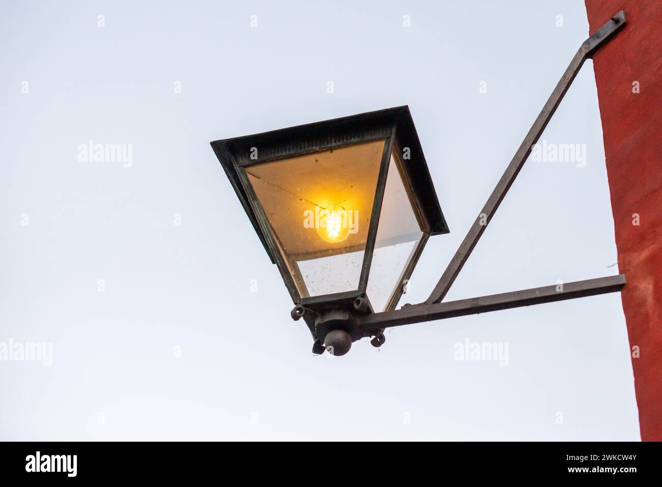 Una lampada da strada compatta su un palo cremisi vicino a una struttura. Foto Stock