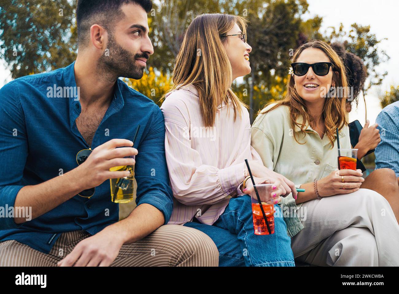 Amici che chiacchierano con bevande rinfrescanti al tramonto - ritrovo sociale alla luce della sera - concetto di relax e stile di vita. Foto Stock