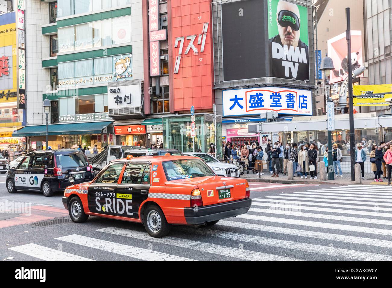 Taxi Orange Toyota sulla stazione di Shibuya mentre la gente aspetta di attraversare, Tokyo, Giappone, Asia, 2023 Foto Stock