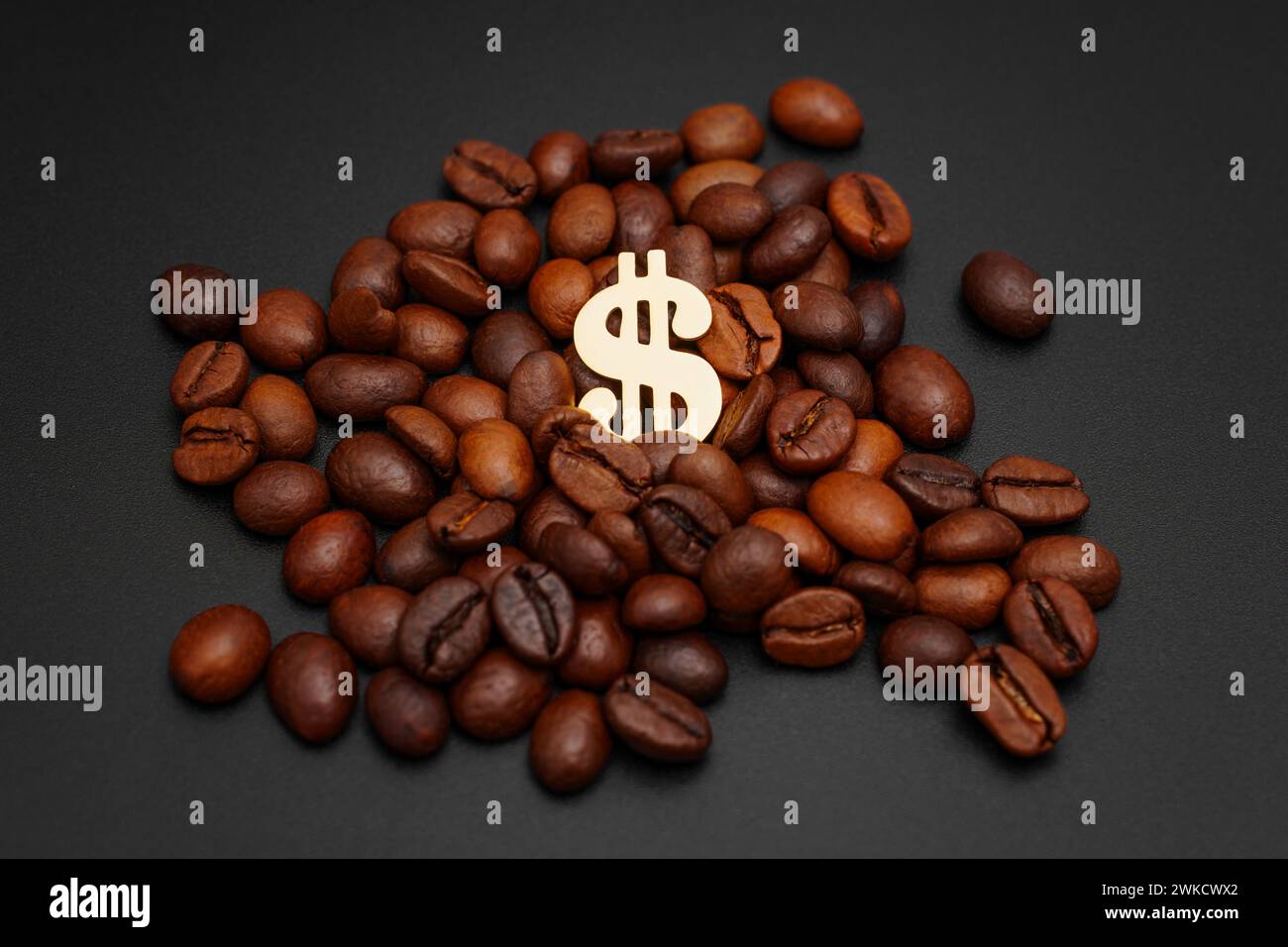 Simbolo del dollaro d'oro situato all'interno di una pila di chicchi di caffè tostati su un elegante sfondo nero. Concetto di rapporto prezzo/gusto del caffè. Foto Stock