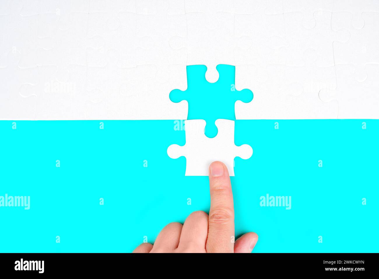 Il momento del trionfo: La mano inserisce delicatamente l'ultimo pezzo in un puzzle. Concetto correlato alla risoluzione dei problemi, al raggiungimento e al successo. Foto Stock