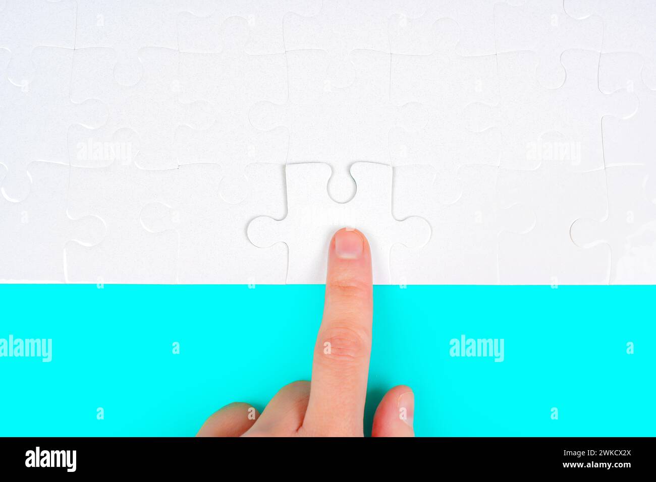 La mano inserisce con cura il pezzo finale nel puzzle. L'essenza del completamento, della determinazione e della realizzazione. Foto Stock