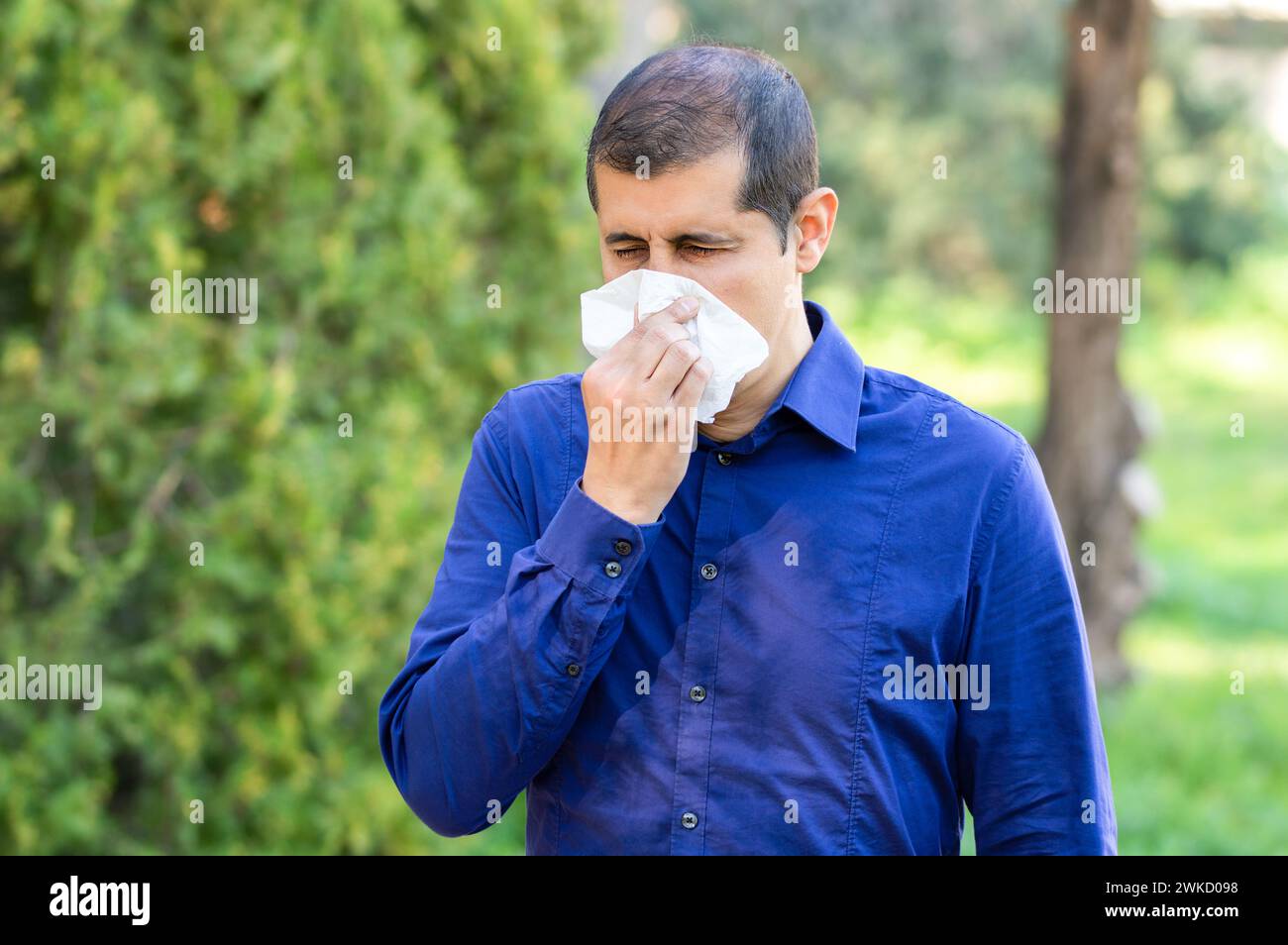 L'uomo malato che soffia utilizzando un tessuto in un parco Foto Stock