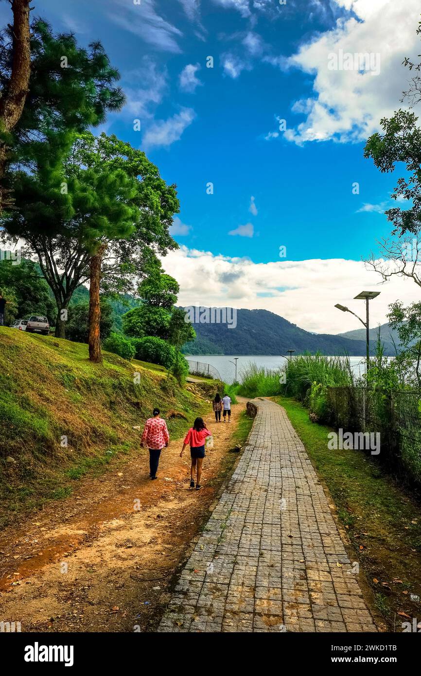 Un gruppo di individui che passeggiano lungo i sentieri accanto al lago Umiam a Meghalaya, in India Foto Stock